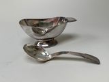 a silver spoon and a silver bowl on a white table