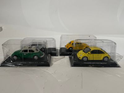trois voitures miniatures sont exposées dans une vitrine posée sur une surface blanche