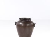 un vase marron muni d'anses, sur un fond blanc