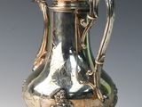 a silver coffee pot sitting on a stand on a table