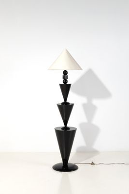une image représentant une lampe noire surmontée d'un abat-jour blanc