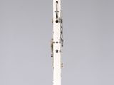 a white and gold clarinet on a clear stand