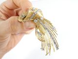a person holding a gold and diamond brooch