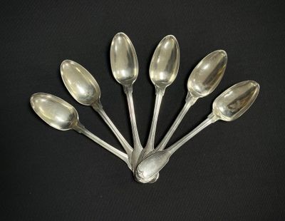 six cuillères en argent sont disposées en rangée sur une surface noire