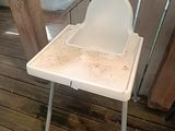a dirty high chair sitting on the deck of a house