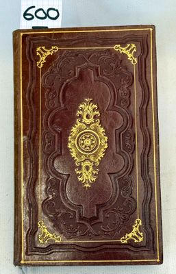 an old book with a gold decoration on it sitting on top of a table