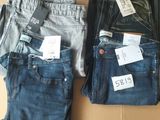 three pairs of jeans are sitting on a cardboard box with price tags