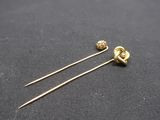 a pair of gold tone hair pins on a black cloth