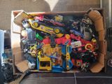 a cardboard box full of assorted toys on the floor