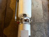 a water heater sitting on a wooden floor next to a trash can