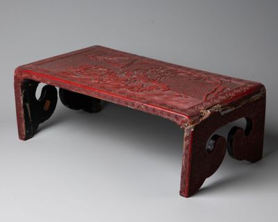 un vieux banc rouge posé sur un sol gris