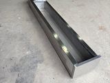 a long metal trough sitting on the floor in a garage