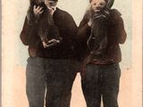 une vieille photo montrant deux hommes tenant un chien dans leurs mains