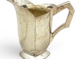 a silver pitcher that is sitting on a white surface