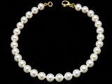a white pearl necklace with a gold clasp on a black background