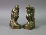 pair of bronze figurines of a man and a woman sitting on a rock