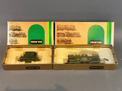 deux boîtes contenant des trains miniatures, posées sur une surface grise