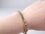 someone wearing a gold chain bracelet on their arm