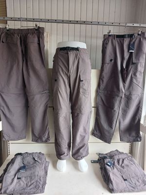 three pairs of pants hanging on a rack in a room
