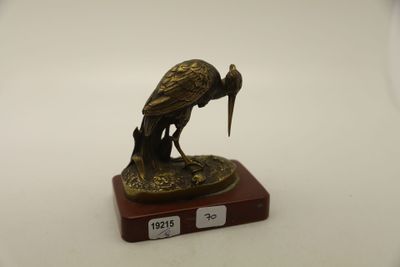 une statue en bronze représentant un oiseau, posée sur un socle en bois