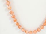 a close up of a necklace with orange beads on a white surface