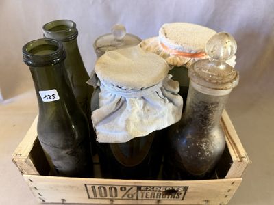 une caisse en bois remplie de bouteilles et de bocaux posée sur une table