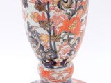 a red and blue vase sitting on a white surface