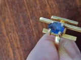 a person holding a ring with a blue stone in it