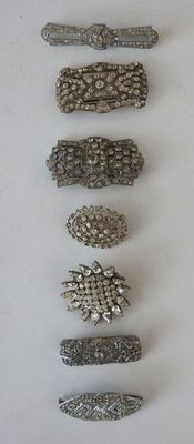 several different types of silver hair clips on a white surface