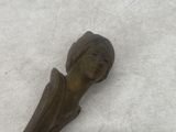 a small bronze statue of a woman on a white surface