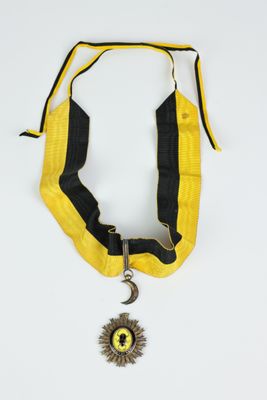 une image représentant un collier jaune et noir orné d'un soleil et d'une lune