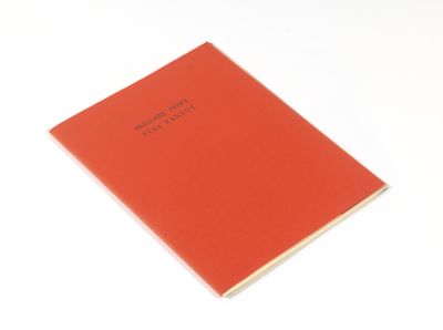 un cahier orange avec une inscription noire, posé sur une surface blanche