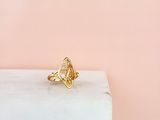 une bague en or posée sur un bloc de marbre, sur fond rose