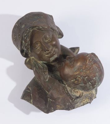 statue en bronze représentant une femme tenant un enfant dans ses bras, posée sur une surface blanche