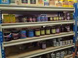 many shelves of paint and other items in the store