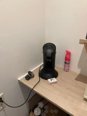 a coffee maker on a small desk in the corner of a room