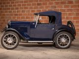 a old blue car parked in front of a brick wall