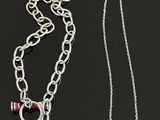 two necklaces with charms on a chain on a black surface