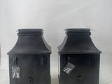 two black metal lanterns with tags on them sitting on a white surface