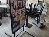 un panneau au milieu d'une pièce où se trouvent des chaises et une table