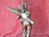 bronze statue of a woman holding a candle on a pedestal