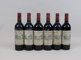 six bottles of wine are lined up on a white surface