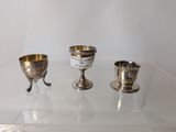 three silver goblets sitting on a glass table