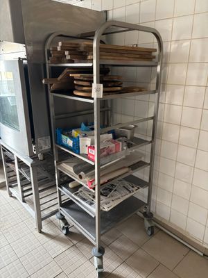Plusieurs plateaux de nourriture sont posés sur un chariot métallique dans une cuisine