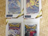 quatre paquets de cartes Pokémon posés sur un plateau en bois