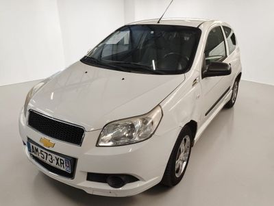 La Chevrolet Aveo blanche est garée dans une pièce blanche.
