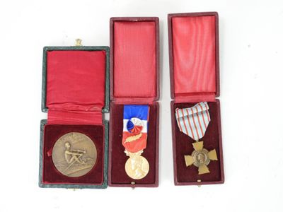 trois médailles et une médaille dans un écrin rouge posé sur un fond blanc