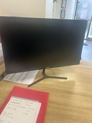 a computer monitor sitting on a desk with a notepad