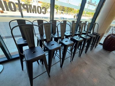 une rangée de chaises en métal noir devant une fenêtre dans un restaurant