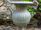 a large urn sitting on the ground in front of a stone wall